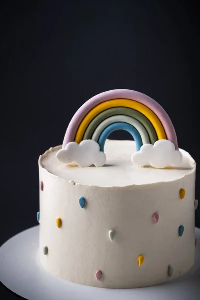 黒を背景にカラフルな魔法の虹で飾られた白いクリームチーズの霜付きの誕生日ケーキ — ストック写真