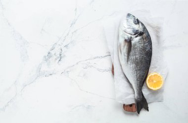 Beyaz mermer arka planda limonlu taze dorado balığı. Düz yatıyordu