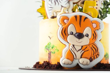 Zencefilli kurabiyeli sarı krem peynirli safari pastası. Beyaz arka planda kaplan ve zebra kurabiyeleri olan Afrika pastası.