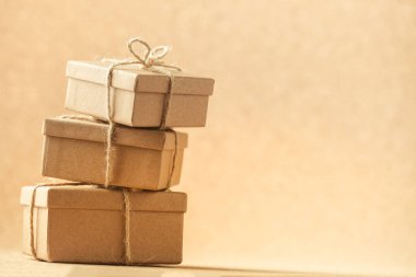 Karton hediye kutuları, sıcak kahverengi arka planda bir sicimle bağlanmış. Doğayı kurtarmak için geri dönüşümlü paketleme.