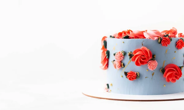 白い背景に赤い花で飾られた青いクリームチーズの霜付きの誕生日ケーキ — ストック写真