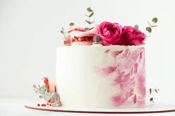 マカロンとバラで飾られたピンクのクリームチーズの霜降りと美しい誕生日ケーキ ハッピーバレンタインデー 白を基調とした記念日ケーキ — ストック写真