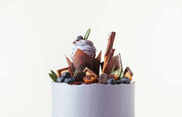 白い背景にカップケーキ ブルーベリーとチョコレートクッキーで飾られたバイオレットクリームチーズの霜付きの誕生日ケーキ — ストック写真