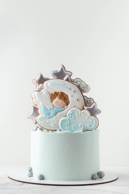 Beyaz arka planda zencefilli kurabiyelerle süslenmiş krem peynirli vaftiz pastası. Ay 'da uyuyan küçük bebek melek. Bebek doğumu kutlaması.