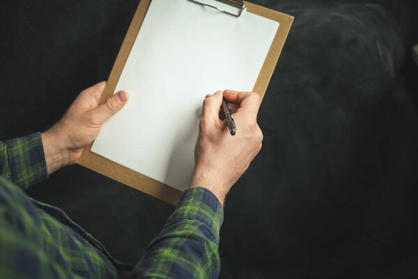 Разнорабочий делает заметки на работе. Доставщик с блокнотом. Мужчина держит в руках пустой блокнот с свободным местом для текста