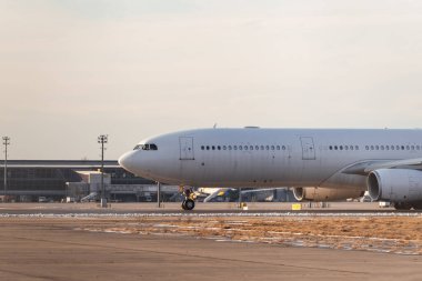 Airbus A330 uluslararası havaalanından kalkıyor. Pistte havayolu üniforması ve logosu olmayan beyaz bir kargo uçağı.
