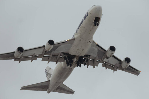 KYIV, UKRAINE - FEBRUARY 03, 2022: Boeing 747 aircraft of Western Global Airlines airborn in the sky. White four engined airplane took off and rectracting the gear. close up shot of airplane landing gear and wing flight controls