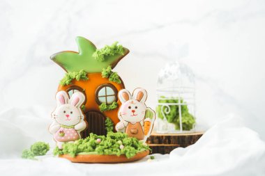 Paskalya tavşanı şeklinde zencefilli kurabiye. Beyaz arka planda şenlikli kremayla süslenmiş.