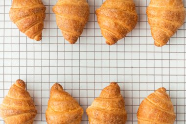 Beyaz arka plandaki metal ızgarada ev yapımı kruvasanların yakın plan çekimi..