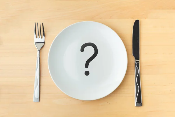 用金属刀叉和刀叉在木制桌子上打上问号的空白白盘 餐厅菜单的背景 等饭的概念 — 图库照片
