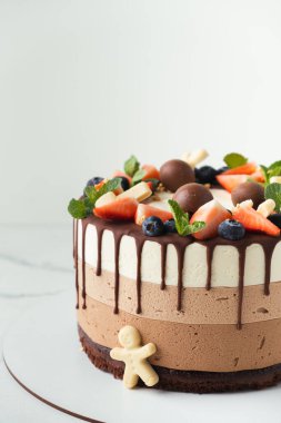 Üzerine yaban mersini, çilek ve çikolata serpiştirilmiş üç çikolata. Beyaz arkaplan.