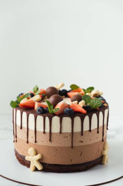 Üzerine yaban mersini, çilek ve çikolata serpiştirilmiş üç çikolata. Beyaz arkaplan.