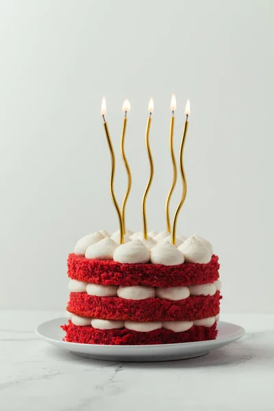 赤いベルベットのスポンジ層と明るい金色のキャンドルで飾られた白いクリームチーズ充填誕生日ケーキ — ストック写真