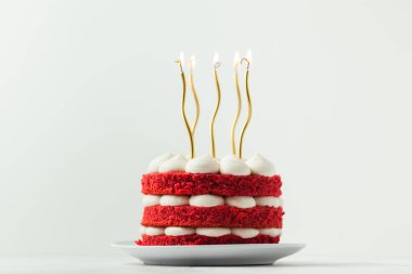 Kırmızı kadife sünger katlı doğum günü pastası ve altın mumlarla süslenmiş beyaz krem peynir.