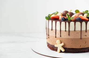 Üzerine yaban mersini, çilek ve çikolata serpiştirilmiş üç çikolata. Beyaz arkaplan.