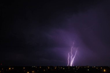 Gece gökyüzünde büyük şimşekler çakan şehir manzarası