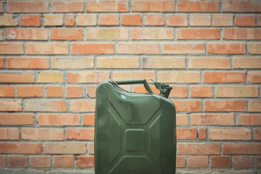 Yeşil Jerrycan, kırmızı tuğla duvara karşı. Benzin dolu bir gaz bidonu. Seyahat ederken yakıt sıkıntısı