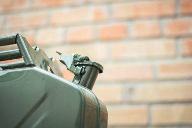Yeşil Jerrycan, kırmızı tuğla duvara karşı. Benzin dolu bir gaz bidonu. Seyahat ederken yakıt sıkıntısı