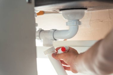 Kanalizasyon ve lavabo sifonunu yakın çekim. Tesisatçı lavabo giderlerini tamir ediyor.