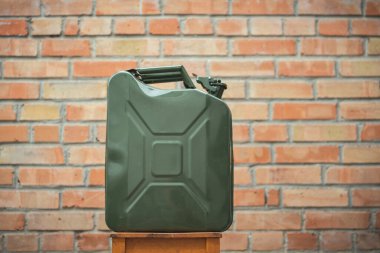 Yeşil Jerrycan, kırmızı tuğla duvara karşı. Benzin dolu bir gaz bidonu. Seyahat ederken yakıt sıkıntısı