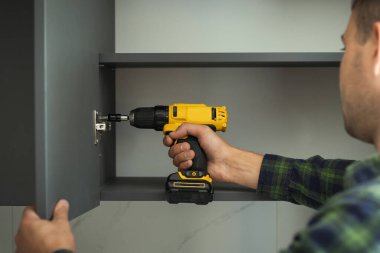 Mobilyacı, dolaba kapı takmak için tornavida kullanır. Yeni mobilya montajı