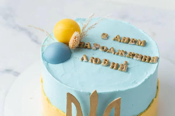 Patriotic birthday cake with yellow and blue cream cheese frosting. Cake for the defender of Ukraine with text on top which means Happy birthday Honey