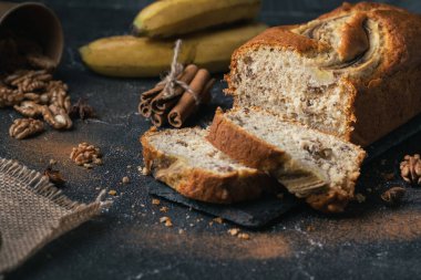 Muzlu turta, muz ve cevizlerin yanında siyah beton arka planda parçalanmış. Ev yapımı hamur işi kavramı.