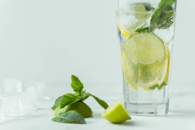Beyaz arka planda cam bardakta naneli ve limonlu mojito kokteyli. Buzlu soğuk yaz içkisi