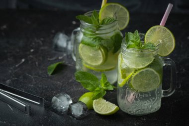 Siyah arka planda cam bardakta naneli ve limonlu mojito kokteyli. Buzlu soğuk yaz içkisi