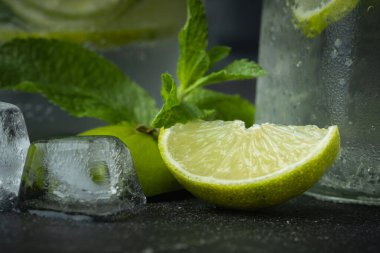 Siyah arka planda cam bardakta naneli ve limonlu mojito kokteyli. Buzlu soğuk yaz içkisi