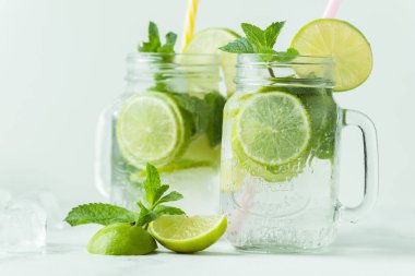 Beyaz arka planda cam bardakta naneli ve limonlu mojito kokteyli. Buzlu soğuk yaz içkisi