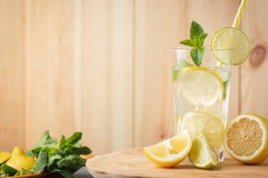 refreshment drink mojito with mint, lemon and lime in a glass on a rustic wooden background. Cold summer drink with ice