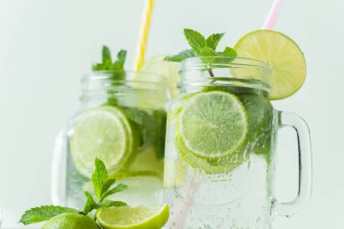 Beyaz arka planda cam bardakta naneli ve limonlu mojito kokteyli. Buzlu soğuk yaz içkisi