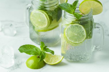 Beyaz arka planda cam bardakta naneli ve limonlu mojito kokteyli. Buzlu soğuk yaz içkisi
