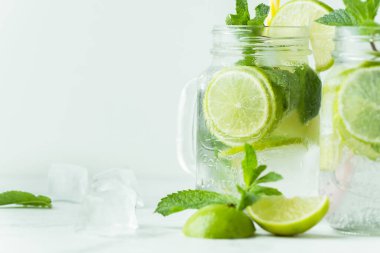 Beyaz arka planda cam bardakta naneli ve limonlu mojito kokteyli. Buzlu soğuk yaz içkisi