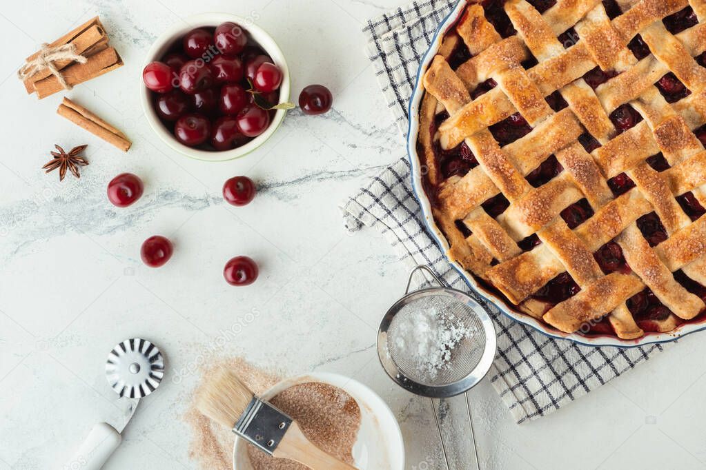 Delicious homemade cherry pie with Flaky Crust sprinkled with powdered sugar on the white marble background. American traditional pastry. Flat lay. Fresh summer berry tart dessert