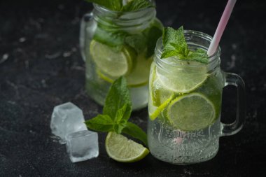 Siyah arka planda cam bardakta naneli ve limonlu mojito kokteyli. Buzlu soğuk yaz içkisi
