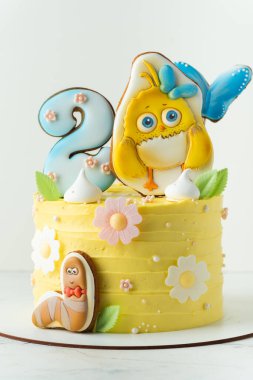 Kyiv, Ukraine - August 17: Birthday cake for a little fan of Como Kids cartoon video. Cake with yellow cream cheese frosting and chick shaped gingerbread cookies