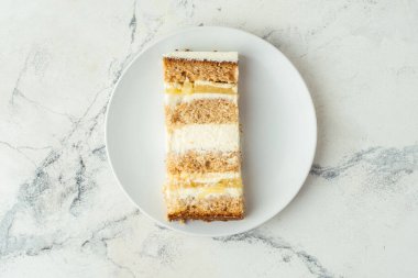 Krem peynirli ve sarı meyveli kremalı katmanlı sünger keki. Beyaz mermer arka plan. Düz yatıyordu. Boş alan