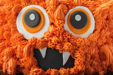 Beyaz arka planda canavar temalı pasta. Beyaz üzerine izole edilmiş portakallı krem peynirli Cadılar Bayramı pastası.