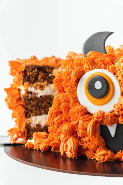 Monster theme cake on the white background. Halloween cake with orange fluffy cream cheese frosting isolated on white