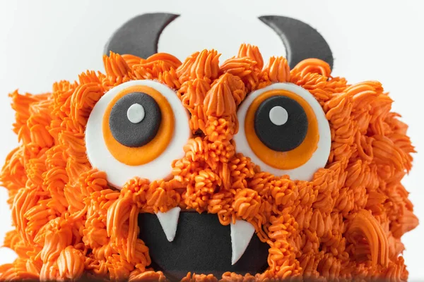 Monster theme cake on the white background. Halloween cake with orange fluffy cream cheese frosting isolated on white