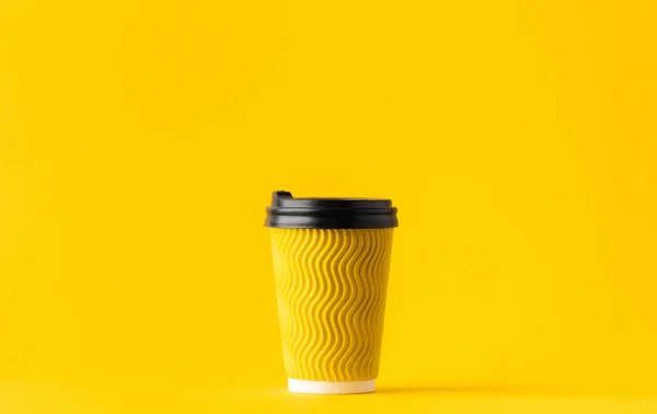 Yellow paper cup of coffee on a yellow background. Disposable paper cup. Save the planet concept. Recycling paper