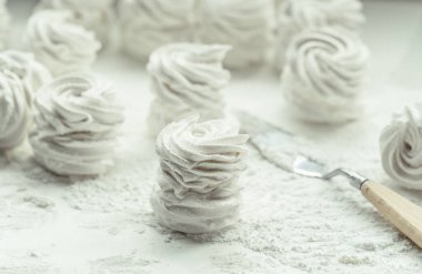 Beyaz arka planda ev yapımı beyaz elmalı marşmelov. Üzerine pudra şekeri serpiştirilmiş parşömen üzerinde ev yapımı sağlıklı kremalı pastalar.