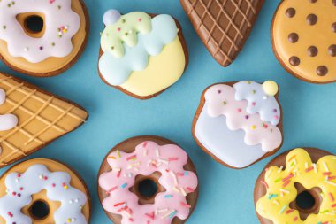 Dondurma şeklinde ev yapımı zencefilli kurabiye, çörek ve pastel renkli kekler. Eski moda pasta arka planı. Mavi arkaplan ile düz uzandı