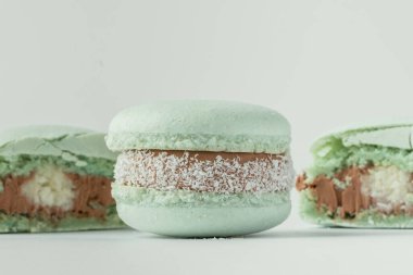 Çikolata ganache ve hindistan cevizi gevreğiyle dolu yeşil yarım dilimli Macro shot. Hindistan cevizi aromalı Fransız kurabiyesi.