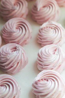 Beyaz arka planda ev yapımı pembe şekerlemeler. Üzerine pudra şekeri serpiştirilmiş parşömen üzerinde ev yapımı sağlıklı kremalı pastalar.