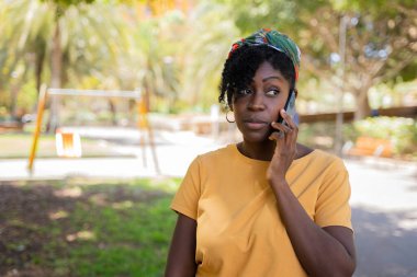 Sokakta cep telefonuyla konuşurken tiksinen siyah bir kadın.