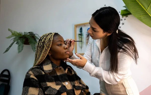 stock image young african american woman putting on makeup