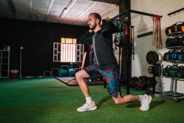 Delikanlı ağırlıkla çömeliyor.